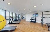 This state-of-the-art fitness center, spanning 890 square feet, offers a comprehensive workout experience. The space is characterized by its modern design, featuring floor-to-ceiling windows that flood the area with natural light and provide stunning city views. The room is outfitted with a wide array of exercise equipment, including treadmills, elliptical machines, stationary bikes, and weight training apparatus. The layout is thoughtfully designed to maximize space utilization while ensuring ample room for movement between stations. The warm wood flooring adds a touch of elegance and comfort to the environment. Recessed lighting fixtures are strategically placed throughout the ceiling, ensuring even illumination across the entire area. Additional amenities include exercise balls, yoga mats, and a wall-mounted TV for entertainment or guided workouts. The center's location at 701 Valencia Ave in Coral Gables, Florida, makes it a convenient fitness destination for residents and potentially hotel guests in the area.