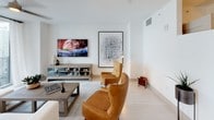 Located at 340 SE 3rd Avenue in Miami's vibrant Brickell district, this single-floor residence showcases a clean, contemporary design characterized by white walls, light-toned tile flooring, and an open, airy layout throughout. The living area serves as the central gathering space, featuring a wall-mounted flat-screen TV, cognac leather wingback chairs, a neutral area rug, and curated abstract artwork that adds visual depth to the minimalist aesthetic.

The kitchen is outfitted with wood-grain cabinetry, stainless steel appliances including a French door refrigerator and range with overhead hood, a white quartz countertop, subway tile backsplash, and an undermount sink — combining both style and functionality. A private balcony, accessible via floor-to-ceiling sliding glass doors, offers sweeping views of Miami's skyline and green spaces below.

The bedrooms are bright and serene, each featuring large windows with sheer curtains that draw in natural light. One bedroom offers direct balcony access with striking high-rise views. The bathroom is finished with a backlit LED vanity mirror, wood-tone cabinetry, a soaking tub with shower combination, and white tile throughout, completing the space with a polished, modern feel.