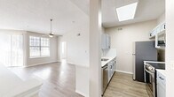 This two-story home offers a well-organized layout across two levels, with the main living areas occupying the upper floor and garage access below. The open-concept kitchen and living room serve as the heart of the home, featuring light hardwood-style flooring, a ceiling fan, and windows that invite natural light throughout. The kitchen is outfitted with soft gray shaker-style cabinetry, a marble-look quartz countertop, a stainless steel undermount sink with a gooseneck faucet, and a full suite of stainless steel appliances including a refrigerator, range, microwave, and dishwasher. A skylight above the kitchen adds an additional source of natural light. A dedicated pantry closet provides convenient storage adjacent to the kitchen. The living area flows openly from the kitchen, offering a spacious and airy feel. Two bedrooms are located on the main floor, each with hardwood-style flooring, ceiling fans, and windows with blinds. The primary bedroom is generously sized with a built-in closet. The bathroom features wood-look flooring, a vanity with storage, and a clean, neutral finish. Carpeted stairs connect the floors, and in-unit laundry is conveniently included. The garage provides additional utility and storage space.
