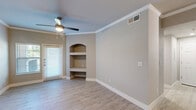 Located at 4699 Fossil Vista Dr in Haltom City, TX, this one-bedroom, one-bathroom unit offers a thoughtfully designed layout across a single floor. Light wood-style flooring runs throughout, complemented by neutral, warm-toned walls and crisp white baseboards and trim that create a clean, cohesive aesthetic.

The combined kitchen and living area serves as the heart of the home. The kitchen features a peninsula with a white countertop and undermount sink, gray cabinetry with gold-toned hardware, stainless steel appliances, and track lighting overhead. The living area benefits from crown molding, a ceiling fan with light, a window with outdoor views, and a distinctive arched built-in shelving niche — an attractive architectural detail that adds character to the space.

The bedroom is well-proportioned, featuring a ceiling fan, a window that invites natural light and greenery views, and a vaulted ceiling that adds a sense of openness. A dedicated closet provides practical storage.

The bathroom is finished with a gray vanity topped with a white countertop, gold accent hardware, wood-style tile flooring, and a full tub-shower combination surrounded by marble-look tile. The outdoor area visible in the floor plan includes a private grassy yard space, a desirable feature for the unit.