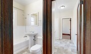 This 2-bedroom, 1-bathroom unit offers a thoughtfully arranged single-floor layout that makes efficient use of its compact footprint. Rich hardwood flooring flows throughout the bedrooms and hallway, complemented by warm-toned wood trim, baseboards, and solid wood doors that lend a classic character to the space.

The spacious primary bedroom is a standout feature, boasting an elegant curved bay window with rich mahogany-stained wood framing that invites generous natural light and offers views of the surrounding neighborhood. Crown molding adds a refined architectural touch. The second bedroom, also featuring hardwood floors and a wood-framed window, includes access to a dedicated closet with a full-length hanging rod — a practical storage solution.

The kitchen is well-appointed with white cabinetry, granite countertops, a stainless steel sink, and a gas range. Tile flooring and a bright window overlooking the exterior keep the space feeling open and functional.

The bathroom features a clean, classic design with white wainscoting, a pedestal sink, a shower-over-tub combination with a window above, and tile flooring. Rich dark wood door trim ties the space to the rest of the unit's traditional aesthetic.

A cast-iron radiator in the second bedroom points to the unit's historic character, blending old-world charm with practical, well-maintained finishes throughout.