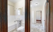 This 2-bedroom, 1-bathroom unit offers a thoughtfully arranged single-floor layout that makes efficient use of its compact footprint. Rich hardwood flooring flows throughout the bedrooms and hallway, complemented by warm-toned wood trim, baseboards, and solid wood doors that lend a classic character to the space.

The spacious primary bedroom is a standout feature, boasting an elegant curved bay window with rich mahogany-stained wood framing that invites generous natural light and offers views of the surrounding neighborhood. Crown molding adds a refined architectural touch. The second bedroom, also featuring hardwood floors and a wood-framed window, includes access to a dedicated closet with a full-length hanging rod — a practical storage solution.

The kitchen is well-appointed with white cabinetry, granite countertops, a stainless steel sink, and a gas range. Tile flooring and a bright window overlooking the exterior keep the space feeling open and functional.

The bathroom features a clean, classic design with white wainscoting, a pedestal sink, a shower-over-tub combination with a window above, and tile flooring. Rich dark wood door trim ties the space to the rest of the unit's traditional aesthetic.

A cast-iron radiator in the second bedroom points to the unit's historic character, blending old-world charm with practical, well-maintained finishes throughout.