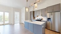 Located at 1180 Canton St in Roswell, GA, this thoughtfully designed 2-bedroom, 3-bathroom residence offers a well-appointed single-floor layout with modern finishes throughout. The open-concept kitchen and living area serves as the heart of the home, featuring gray shaker cabinetry, white quartz countertops, a central island with a sink, subway tile backsplash, stainless steel appliances, and warm light wood flooring. Pendant lighting adds a refined touch overhead. The living area extends toward large glass sliding doors that lead to a covered outdoor porch with concrete flooring and a stylish pendant light fixture. Abundant windows fitted with blinds flood the interior with natural light and offer views of the surrounding neighborhood. The generously sized primary bedroom features plush carpeting and multiple windows, accompanied by a well-appointed en-suite bathroom with a dual-sink vanity, gray cabinetry, white quartz counters, framed mirrors, and a tiled walk-in shower. The second bedroom is equally bright with carpet flooring and ample natural light. Additional bathrooms include a full tub-shower combo with white subway tile. Closets feature wire shelving for organized storage, and a hallway connects all spaces efficiently.