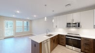 This well-appointed one-bedroom, one-bathroom residence at 200 Middletown Blvd in Langhorne, PA offers a thoughtfully designed layout with modern finishes throughout. The open-concept kitchen serves as the heart of the home, showcasing a two-tone design with crisp white upper cabinetry and warm wood-toned lower cabinets. A peninsula with a white quartz countertop provides additional workspace and casual dining potential, while pendant lighting adds a refined touch overhead. Stainless steel appliances — including a French door refrigerator, electric range, over-the-range microwave, and dishwasher — complete the space. Light hardwood-style flooring flows through the kitchen and living area, creating a bright, cohesive feel. The bedroom offers plush carpeting, neutral warm-toned walls, and a window with blinds that allows natural light to filter in. A dedicated closet provides convenient storage. The bathroom features a wood-toned vanity with a white quartz countertop, an undermount sink, a large mirror, and a tiled tub/shower combination. Clean tile flooring ties the bathroom together with a contemporary aesthetic. A private outdoor area is also accessible from the main living space, as visible from the dollhouse view.