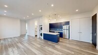 Unit 8B at 715 Park Ave in East Orange, NJ is a well-appointed 2-bedroom, 3-bathroom residence offering a thoughtfully designed open-concept floor plan. Light-toned hardwood flooring flows throughout the space, complemented by crisp white walls and recessed lighting that create a bright, modern atmosphere. The open living area features multiple windows with city views, flooding the space with natural light.

The kitchen is a standout feature, showcasing bold navy blue cabinetry, a matching center island with white countertops, and a blue tile backsplash. Stainless steel appliances — including a refrigerator, range, microwave, and dishwasher — complete the modern aesthetic. Geometric pendant lighting adds a designer touch above the island. A stacked in-unit washer and dryer is conveniently integrated near the kitchen.

The primary bedroom offers generous proportions with multiple windows framing open views. Additional bedrooms are well-sized with ample natural light and closet access. The bathrooms are elegantly finished, featuring subway tile walls, large-format stone-look floor tiles, and contemporary vanities. One bathroom includes a soaking tub with a rain showerhead and matte black fixtures, while another serves as a half bath with a sleek pedestal vanity.
