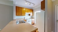 Located at 179 Emmaus Rd in Marysville, Ohio, this two-story home offers a well-organized layout with practical features spread across both levels. The kitchen is equipped with warm oak cabinetry, a peninsula with countertop overhang for seating, a stainless steel double sink, and white appliances including an electric range and refrigerator. Track lighting illuminates the workspace, and light hardwood-style flooring adds a clean, cohesive look throughout the kitchen area. The main living area is generously proportioned, with plush carpet, crown molding, and a sliding glass door that invites natural light and provides views of the surrounding greenery. A charming built-in shelving nook is tucked beneath the staircase, offering functional storage without sacrificing floor space. Upstairs, the bedrooms are carpeted and well-lit by multiple windows, creating bright and comfortable rooms. One area features a built-in desk, ideal for a home office or study space. The bathroom includes a long dual-sink vanity with oak cabinetry, a wide mirror, and hardwood-style flooring, providing ample counter space. Neutral wall tones and clean white trim are consistent throughout the home, lending a calm and cohesive aesthetic to every room.
