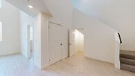 Located at 8521 Sepulveda Blvd in Los Angeles, CA, this modern two-story home offers a thoughtfully designed layout spread across two floors. The ground floor serves as the main living area, featuring light wood-tone flooring throughout and a clean, contemporary aesthetic defined by crisp white walls and abundant natural light. The kitchen is a standout feature, equipped with stainless steel appliances including a French door refrigerator with ice maker, dishwasher, range, and built-in microwave. Two-toned cabinetry — white upper cabinets paired with gray lower cabinets — complement the light countertops and subway tile backsplash, creating a fresh, modern feel. A hallway connects the main living spaces and leads to the full bathroom, which features gray vanity cabinetry, light wood-look flooring, and clean white walls. A staircase leads to the upper floor, where dramatic vaulted ceilings and angled rooflines create a striking architectural character. The spacious primary bedroom on this level is carpeted for comfort and benefits from multiple windows that bring in natural light. Light wood flooring continues through the upper hallway, which features high angled ceilings that add volume and visual interest to the space.