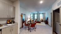 This single-floor residence at 1877 Riverside Pkwy in Douglasville, GA offers a well-designed layout with modern finishes throughout. The kitchen is a standout feature, outfitted with light wood-grain cabinetry extending to the ceiling, granite countertops, a tiled backsplash, and a full suite of stainless steel appliances including a refrigerator, electric range, built-in microwave, and dishwasher. Rich hardwood-style flooring grounds the kitchen and transitions into the open dining area, creating a seamless connection between cooking and entertaining spaces. The living room is carpeted and features a ceiling fan, multiple windows that invite natural light, and generous wall space suited for artwork. An open sightline connects the living and dining areas to the kitchen, enhancing the sense of space. The bedroom is appointed with plush carpet, a ceiling fan, and a bold teal accent wall that adds a vivid focal point to the room. Natural light filters in through windows dressed with curtain panels. The bathroom features hardwood-style flooring, a vanity with a single sink, and a shower-tub combination, all presented in a clean, neutral palette that complements the home's contemporary aesthetic.