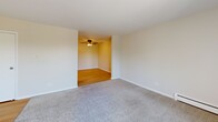 Located at 1440 S Neltnor Blvd in West Chicago, IL, this one-bedroom, one-bathroom unit offers a practical and comfortable layout across a single floor. The living room is generously sized, featuring soft carpeting, a wall-unit air conditioner, baseboard heating, and a sliding glass door that opens onto a private balcony with outdoor views — allowing natural light to fill the space. An exposed brick accent wall adds a subtle architectural detail to the living area.

The kitchen is well-appointed with light hardwood-style flooring, gray shaker-style cabinetry, white countertops, a stainless steel refrigerator, and a built-in sink. A white-painted brick wall provides a clean, bright backdrop. Overhead lighting keeps the space well-lit throughout.

The bedroom is a comfortable size, finished with plush carpeting, a dedicated window for natural light, baseboard heating, and a ceiling fan. A closet provides additional storage.

The bathroom features gray vanity cabinetry, a vanity mirror with lighted fixture, a toilet, and a tub/shower combination with tiled surround, all set on hardwood-style flooring. The hallway connecting the rooms continues the cohesive flooring theme, creating a smooth flow throughout the unit.