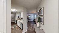This single-floor residence offers a thoughtfully designed open-concept layout that connects the kitchen, dining, and living areas seamlessly. The galley-style kitchen is well-equipped with white cabinetry, light countertops, stainless steel appliances including a range and microwave, and a double sink. Wood-look plank flooring runs throughout the main living areas, adding warmth and visual continuity.

The living room features crown molding, a ceiling fan, and ample natural light from large windows, creating an inviting and comfortable gathering space. A dedicated entryway with a console and decorative wall art provides a welcoming transition into the home.

Two bedrooms are carpeted for comfort, each featuring large windows with horizontal blinds that allow generous natural light while maintaining privacy. Ceiling fans are present in the bedrooms, enhancing ventilation. Both rooms offer sufficient space for full bedroom furniture.

Two bathrooms serve the unit, each featuring white cabinetry with light countertops, a tub-shower combination, wood-look flooring, and clean, neutral finishes throughout. The textured ceilings are consistent across the unit, and the overall color palette of soft grays and warm whites creates a cohesive, modern aesthetic.