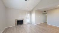 This single-story, 3-bedroom, 2-bathroom home offers a thoughtfully organized layout with a neutral color palette and light-toned flooring throughout the main living areas. The living room serves as the centerpiece of the home, boasting striking vaulted ceilings that amplify the sense of space and openness. A tile-surround fireplace anchors the room, while a ceiling fan, exterior door, and windows allow for natural light and outdoor access. The kitchen is equipped with white shaker-style cabinetry, light countertops, a gray subway tile backsplash, and black appliances including a refrigerator and range, complemented by a stainless steel microwave. The primary bedroom features vaulted ceilings, plush carpeting, a ceiling fan, and a window with outdoor views. Additional bedrooms are carpeted and include closets with built-in shelving. The bathrooms are clean and functional, with one featuring a full tiled tub-shower combination and wood-look flooring. A dedicated laundry area accommodates a full-size side-by-side washer and dryer with overhead shelving. The hallway connects the rooms efficiently, completing a practical and comfortable floor plan.