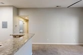 Located at 6710 Collins Road in Jacksonville, FL, this one-bedroom, one-bathroom unit offers a practical and well-appointed layout across a single floor. The open-concept kitchen and living area serves as the heart of the home, featuring granite-look countertops with a breakfast bar peninsula, white shaker cabinetry, a classic subway tile backsplash, and a full suite of stainless steel appliances including a range, over-the-range microwave, and refrigerator. Wood-look flooring runs through the kitchen and utility areas, while plush carpeting adds comfort to the living room and bedroom. The bedroom is a well-sized retreat with a ceiling fan, natural light from a window with blinds, and a double-door closet providing ample storage. The bathroom includes a full tiled tub-shower combo with brushed nickel fixtures and a granite-topped vanity. A dedicated in-unit laundry room houses a full-size washer and dryer alongside the water heater. Additional highlights include a hallway connecting all rooms seamlessly, a private balcony for outdoor enjoyment, and neutral tones throughout that create a clean, move-in-ready ambiance.