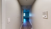 Located on St. Joseph Creek Road in Lisle, Illinois, this single-floor unit offers a straightforward, functional layout with a cohesive design throughout. Hardwood-style flooring runs consistently across the main living areas and hallway, contributing to a clean, unified aesthetic.

A narrow entryway hallway leads into the main living space, which is open and generously sized. The living area features neutral-toned walls, white trim, and two sources of natural light — a standard window and a large sliding glass door fitted with vertical blinds, allowing for ample daylight and outdoor access. A wall-mounted heating unit is also present in this room.

The kitchen is equipped with dark-toned cabinetry featuring modern hardware, a stainless steel sink, a subway tile backsplash, an electric range, a built-in microwave, and a dishwasher. Light-toned flooring in the kitchen contrasts subtly with the rest of the unit.

The bathroom includes a tub-shower combination with floor-to-ceiling large-format tile surround, a dark wood vanity with a basin sink, light wood-style flooring, and standard fixtures. The overall ambiance of the unit is clean, modern, and move-in ready.