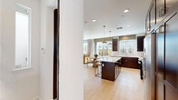 Located at 320 N Airport Way in Manteca, California, this two-story home offers a well-organized layout spread across two floors. The ground floor houses an attached garage with direct interior access, while the main living areas occupy the more expansive upper level. The open-concept kitchen and living room serve as the heart of the home, featuring rich dark-wood cabinetry, white quartz countertops, stainless steel appliances, a central island with seating, and light hardwood flooring that extends throughout. The living room is finished with a neutral gray accent wall and recessed lighting, creating a warm, contemporary atmosphere. Three bedrooms are situated on the upper floor, each carpeted and filled with natural light from well-placed windows. A standout secondary bedroom features a bold blue-and-white geometric accent wall. The generously sized primary bedroom includes access to a walk-in closet with built-in shelving and a private en-suite bathroom with dark wood vanity cabinetry, white countertops, tile flooring, and a glass-enclosed shower. The dedicated laundry room includes side-by-side washer and dryer units, light hardwood flooring, and upper dark-wood cabinetry for added storage. With four full bathrooms and thoughtful finishes throughout, this home combines practical function with modern design.