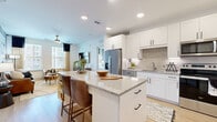 This single-floor residence offers a thoughtfully designed layout across two bedrooms and four bathrooms, making efficient use of its footprint without sacrificing comfort or style. The open-concept kitchen and living area serves as the heart of the home, where light wood-tone flooring, recessed lighting, and a neutral color palette create a clean, contemporary atmosphere. The kitchen is outfitted with white shaker cabinetry, granite countertops, stainless steel appliances, and a central island with seating — an ideal configuration for both daily living and entertaining. The adjacent living room receives natural light through large windows and provides a relaxed yet refined setting.

The primary bedroom offers a comfortable retreat, featuring plush carpeting, dual windows with views to the exterior, a ceiling fan, and direct access to a well-appointed en-suite bathroom. The primary bath includes a dual-sink vanity with granite countertops, white cabinetry with matte black hardware, and a tiled shower. A walk-in closet with built-in shelving and dual hanging rods provides organized storage. The additional bedroom and remaining bathrooms maintain the same consistent, modern finish throughout. A dedicated laundry room houses a full-size washer and dryer with overhead shelving for added convenience.