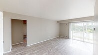 Located at 2094 Lac Du Mont Dr in Haslett, Michigan, this single-floor residence offers a practical and well-appointed layout designed for comfortable everyday living. The open living and dining area is finished with light-toned luxury vinyl plank flooring that extends throughout the main living spaces, creating a clean and cohesive aesthetic. A large sliding glass door floods the living area with natural light and provides access to an outdoor deck, offering pleasant views of the surrounding landscape. A chandelier accent in the dining area adds a subtle decorative touch. The galley-style kitchen is efficiently designed, featuring warm wood cabinetry, granite countertops, black appliances including a gas range and refrigerator, and a deep undermount sink. Conveniently tucked just off the kitchen is an in-unit stacked washer and dryer. The bedrooms are carpeted for added comfort, with multiple rooms offering generous proportions and large windows that bring in ample natural light and outdoor views. Closet space is well-distributed, with bifold doors featured in several rooms. The bathroom is cleanly appointed with a vanity and hardwood-style flooring. Neutral tones throughout the home create a versatile backdrop suitable for a variety of interior styles.