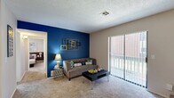 Located at 12901 S Western Ave in Oklahoma City, OK, this 2-bedroom, 2-bathroom residence offers a thoughtfully arranged single-level layout. The living room serves as the heart of the home, featuring a striking bold blue accent wall, a classic brick fireplace, textured ceilings, and a sliding glass door that opens to an outdoor balcony, filling the space with natural light. Soft carpeting runs throughout the main living areas and bedrooms, adding warmth underfoot. The primary bedroom is a comfortable retreat, complete with a ceiling fan, a built-in closet with ample shelving, and natural light from a window. The second bedroom also features carpet flooring, a window, and a well-organized closet with dual hanging rods. Both bathrooms are functional and clean, each featuring a tub-shower combination. One bathroom includes warm wood cabinetry, a granite-style countertop, dark hardwood-style flooring, and generous vanity storage. The kitchen, visible from the floorplan overview, is conveniently positioned adjacent to the living area. Overall, the space offers a practical and comfortable layout well-suited for everyday living in a residential Oklahoma City community.
