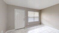 This well-appointed 2-bedroom, 1-bathroom single-story home offers a clean, modern aesthetic throughout its thoughtfully organized floor plan. The interior is unified by striking marble-style porcelain tile flooring that runs seamlessly through every room, lending a bright and polished look to the entire space.

The living room serves as the welcoming heart of the home, featuring a large window dressed with horizontal blinds that invites natural light and a front entry door providing convenient access. The neutral warm-greige wall tones create a calm, versatile backdrop throughout.

The primary bedroom is generously proportioned, offering ample space for furnishings, and is illuminated by a window with outdoor views. The second bedroom is equally comfortable, also benefiting from natural light through its own window. Both rooms feature the same consistent marble-style tile flooring and neutral wall palette.

A dedicated hallway connects the living spaces to the private areas of the home, which include a closet for additional storage. The kitchen features a pass-through window with cabinetry above, a granite-style countertop, and a sink — a compact yet functional setup.

The bathroom is finished with a granite-topped vanity with built-in cabinetry, a large wall mirror, and a tub-shower combination with marble-style tile surround, maintaining the cohesive design language found throughout the home.
