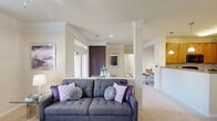 This single-floor, 2-bedroom, 2-bathroom residence in West Columbia, SC offers a well-designed layout that maximizes comfort and functionality. The open-concept living area serves as the heart of the home, highlighted by a bold deep-purple accent wall, crown molding, ceiling fan, and large windows that fill the space with natural light. Decorative columns frame the transition between the living room and the adjoining areas, adding architectural interest throughout.

The kitchen is well-equipped with warm honey-toned cabinetry, granite-style countertops, black appliances including a range, microwave, and refrigerator, and durable wood-look flooring. A breakfast bar with pendant lighting connects the kitchen to the central corridor, making it ideal for both cooking and entertaining.

The spacious primary bedroom features a vaulted ceiling, a ceiling fan, a striking purple accent wall, plush carpeting, and a dedicated closet. The second bedroom is equally comfortable and well-lit. Both bathrooms include vanities with granite-style countertops and warm wood cabinetry, with one bathroom offering a full tub-shower combination and wood-look flooring.

Additional highlights include a dedicated in-unit laundry room with a full-size washer and dryer, two closets for ample storage, and a cohesive neutral color palette accented with bold design choices throughout.