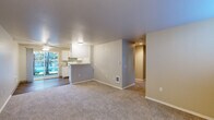 This single-story home offers a practical and well-organized layout across four bedrooms, two full bathrooms, two hallways, and a dedicated walk-in closet. The open-concept living and dining area flows seamlessly into the kitchen, which features white cabinetry, a peninsula counter, and white appliances. A sliding glass door in the living area fills the space with natural light and provides direct access to the outdoors. Neutral-toned carpet covers the living areas and bedrooms, while the kitchen and dining zone transition to hardwood-style flooring.

The bedrooms are carpeted and feature neutral wall tones, with several rooms benefiting from windows fitted with white blinds that allow for natural light and outdoor views. The primary bedroom includes access to a spacious walk-in closet outfitted with extensive wire shelving units on both sides, offering generous storage capacity.

Both bathrooms are finished consistently, each featuring a tub-shower combination, a vanity with a speckled countertop, white cabinetry, a wall mirror, and wood-look flooring. The clean, bright aesthetic maintained throughout both bathrooms adds a functional yet polished feel to the home. Two hallways connect the various rooms efficiently, contributing to the home's straightforward and accessible floor plan.
