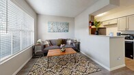 This single-story residence at 11500 Green Plaza Dr in Houston, Texas offers a well-organized floor plan designed for comfortable everyday living. The living room serves as a welcoming central space, featuring wood-look flooring, neutral-toned walls, and windows fitted with blinds that allow natural light to filter through. A pass-through opening connects the living area directly to the kitchen, enhancing the open feel between the two spaces. The kitchen is equipped with a gas range, overhead ventilation hood, refrigerator, and a peninsula with a light stone-finish countertop. Subway tile backsplash and gray cabinetry give the kitchen a clean, contemporary look, while an adjacent dining nook provides a cozy area for meals. A second versatile room with tile flooring and vertical blinds offers flexible use as a bedroom, office, or additional living space. The primary bedroom is carpeted and includes a window for natural light, along with access to a walk-in closet featuring built-in shelving. The bathroom is well-appointed with a wide vanity, quartz-style countertop, white shaker-style cabinetry with brushed nickel hardware, and a large mirror. Textured ceilings are consistent throughout, and wood-look flooring flows through the main living areas. A hallway thermostat and built-in shelving nook add practical details to this thoughtfully laid-out Houston home.