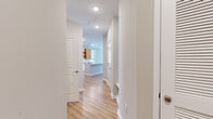This single-floor residence showcases a clean, contemporary design highlighted by light wood-tone flooring that flows consistently throughout the space. A welcoming hallway leads into the open-concept kitchen and living area, the clear centerpiece of the unit. The kitchen is well-appointed with warm wood-grain upper cabinetry, crisp white lower cabinets, a subway tile backsplash, and granite countertops extending across both the perimeter surfaces and a generously sized central island. Stainless steel appliances, including a gas range, built-in microwave, dishwasher, and French door refrigerator, complete the kitchen. Pendant lighting above the island and recessed ceiling lights provide layered illumination, while a nearby window admits ample natural light.

The living area opens to a private balcony through sliding glass doors, flanked by additional windows that offer outdoor views and further brighten the space. A ceiling fan serves both the living area and one of the additional rooms. Each bedroom-sized room features neutral walls, generous windows with blinds, and convenient closet access, including a walk-in closet with wire shelving. The bathroom includes a granite-topped white vanity with an undermount sink and a soaking tub with tile surround, maintaining the home's cohesive, modern aesthetic throughout.