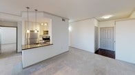This single-floor residence offers a well-organized layout with a practical blend of living spaces. The kitchen is outfitted with stainless steel appliances, including an electric range with a matching over-the-range microwave, and a refrigerator. White shaker-style cabinetry pairs with dark granite-look countertops and a classic white subway tile backsplash. A pass-through counter with pendant lighting connects the kitchen to the living area, creating an open, cohesive feel suited for everyday living and entertaining.

The living area features neutral-toned carpet and open sightlines toward the hallway and bedrooms. The bedrooms are carpeted and bright, each featuring ceiling fans with integrated lighting and windows dressed with horizontal blinds that allow ample natural light. At least one bedroom includes a sliding-door closet with built-in shelving, while another features a walk-in closet. One room benefits from multiple windows and a private exterior door, adding versatility.

The bathroom is appointed with dark subway tile surrounding a soaking tub and shower combination, accented by a curved chrome shower rod, creating a bold contrast against the white fixtures. Overall, the space maintains a clean, neutral aesthetic with consistent finishes throughout.