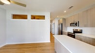 Located at 4710 Mint Leaf Ln in Raleigh, NC, this single-floor residence offers a clean, modern design with a thoughtful open layout. The living and kitchen areas share a connected, open-concept space finished with warm hardwood-style flooring. A distinctive architectural detail — a pair of interior clerestory windows positioned high on the shared wall — allows light to pass between rooms and adds a unique visual element to the design. Ceiling fans are present in the main living areas, contributing to both comfort and airflow.

The kitchen is well-appointed with light wood cabinetry, stainless steel appliances including a refrigerator, over-the-range microwave, and electric range, complemented by a white countertop island that provides additional prep and seating space. A white subway tile backsplash adds a crisp, contemporary touch.

The bedrooms feature plush carpeting and are serviced by a spacious walk-in closet with wire shelving systems, accessed through elegant double panel doors. The bathroom is bright and clean, showcasing light wood-look flooring, a white soaking tub with shower combination, modern fixtures, and a wood-toned vanity with ample counter space. Recessed lighting throughout ensures a well-lit interior across all areas of the home.