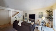 Located at 675 Alvarado Ave in Davis, California, this two-story residence offers a practical and well-organized layout across both levels. The living room serves as the central gathering space on the main floor, featuring textured ceilings, neutral wall tones, and carpet flooring. A staircase is visible from the living area, connecting to the upper level, while a sliding glass door provides access to the outdoors and allows natural light to fill the room.

The galley-style kitchen is efficiently designed with ample white cabinetry lining both walls, generous counter space, and white appliances including a range, microwave, dishwasher, and refrigerator. A utility area with washer and dryer hookups is accessible directly from the kitchen.

The bedrooms are spacious and carpeted, each equipped with ceiling fans with integrated lighting and windows fitted with vertical blinds. The rooms comfortably accommodate multiple beds, making them well-suited for shared living arrangements.

The full bathroom features a wide vanity with extended countertop space, a large mirror, and a shower-tub combination. Throughout the residence, the neutral color palette and textured ceilings contribute to a consistent, understated aesthetic.