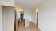 Located at 609 Hughson St N in Hamilton, Ontario, this thoughtfully designed one-bedroom, one-bathroom unit offers a compact yet functional layout across a single floor. Light hardwood-style flooring runs throughout, complementing the clean white walls and creating a bright, cohesive aesthetic.

The open-concept kitchen is a standout feature, equipped with stainless steel appliances including a range, built-in microwave, dishwasher, and refrigerator. Cabinetry in a warm wood-grain finish is paired with smooth white upper cabinets and a horizontal subway tile backsplash. A central kitchen island provides additional counter space and adds to the open feel of the living area. Large windows allow natural light to fill the space, with views of the surrounding urban streetscape.

The bedroom is a well-proportioned retreat featuring mirrored sliding closet doors with built-in wire shelving, maximizing storage in an efficient footprint.

The bathroom is finished to a modern standard, featuring a white vanity with an undermount sink, a framed mirror, and a soaker tub with a marble-look tile surround extending to the ceiling — a refined touch that elevates the overall design.

A bold blue entry door adds a distinctive accent at the entrance, while the clean, neutral palette throughout makes this unit a versatile and move-in-ready space in the heart of Hamilton.