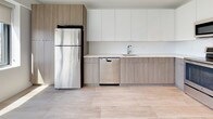 Unit 303 is a thoughtfully designed 1-bedroom, 1-bathroom residence that blends modern aesthetics with functional living. The open-concept layout is anchored by light-toned wood-style tile flooring that flows seamlessly through the main living and kitchen areas, creating a bright, cohesive feel throughout.

The kitchen is a standout feature, outfitted with two-tone cabinetry — sleek white upper cabinets paired with warm wood-finish lower cabinets — complemented by light stone countertops and a clean white backsplash. A full suite of stainless steel appliances includes a refrigerator, electric range, over-the-range microwave, and dishwasher, providing a complete and contemporary cooking space.

The bedroom offers a comfortable, carpeted retreat filled with natural light from a large picture window that frames outdoor views, lending the room an open and airy quality.

The bathroom is finished with wood-look tile flooring that echoes the main living areas, and features a glass-enclosed walk-in shower adorned with elegant veined tile surround, adding a refined touch to the space.

Overall, Unit 303 presents a clean, modern interior with consistent finishes, ample natural light, and a well-organized floor plan suited for comfortable everyday living.