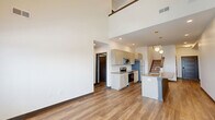 Located at 2136 Central Ave in Indianapolis, this contemporary two-story home offers 3 bedrooms, 2 bathrooms, and a versatile loft spread across two floors. The main floor is anchored by a striking open-concept kitchen and living area featuring soaring double-height ceilings, warm wood-look flooring, and abundant natural light. The kitchen is equipped with stainless steel appliances, taupe shaker-style cabinetry, a tile backsplash, and a central island with a built-in sink and pendant globe lighting — ideal for both cooking and entertaining. A staircase with dark wood accents leads to the upper level, where the loft overlooks the main living space and is bathed in natural light from large windows with outdoor views. The bedrooms are well-proportioned, with the primary offering generous closet space. Additional closets throughout the home provide ample storage. The bathrooms feature tile-surround tub-shower combinations, wood-look flooring, and clean, modern vanities. A dedicated laundry area adds everyday convenience. The home's modern aesthetic is carried throughout with dark-trimmed panel doors, recessed lighting, and a cohesive neutral color palette.