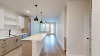 Located at 11401 Biography Way in Orlando, FL, this well-designed one-bedroom, one-bathroom residence offers a thoughtful layout across a single floor. The open-concept living area seamlessly connects the kitchen, dining, and living spaces, creating an inviting and functional environment. Warm hardwood-style flooring flows throughout, complementing the neutral color palette and clean architectural lines.

The kitchen is a standout feature, boasting two-tone cabinetry with white upper cabinets and natural wood-tone lower cabinets, stainless steel appliances including a refrigerator, range, microwave, and dishwasher, a white quartz countertop island, and stylish black pendant lighting. The living area is bathed in natural light through large windows and a glass door leading to the private balcony, and is equipped with a ceiling fan.

The spacious bedroom features hardwood-style flooring, dual windows with natural light, and a ceiling fan, along with access to two closets. The bathroom is finished with white shaker-style cabinetry, a white quartz vanity, matte black hardware, and a soaking tub with shower. Additional conveniences include an in-unit laundry area, making this residence both practical and polished in every detail.