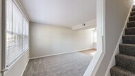 Located at 614 Peninsula Dr in Newport News, Virginia, this two-story home offers a functional and well-organized layout across two floors. The main level features a bright living room with plush carpet flooring, neutral walls, and large windows fitted with blinds that invite ample natural light. Adjacent to the living area, the kitchen is a standout space, showcasing dark espresso cabinetry, stone-look countertops, warm hardwood-style flooring, and black appliances including a range and refrigerator. A convenient back door provides direct outdoor access from the kitchen area. A staircase connects the main level to the upper floor, which houses both bedrooms, the bathroom, a hallway, and a closet. The primary bedroom is a comfortable, well-lit space with carpet flooring, crown molding, and a ceiling fan. The second bedroom mirrors a similar design with carpet, multiple windows, and a ceiling fan. The full bathroom features classic white subway tile from floor to ceiling, a soaking tub, pedestal sink, and a bright window. Throughout the home, consistent neutral tones, crown molding, and carpet or hardwood-style flooring create a cohesive and clean aesthetic. A utility room rounds out the practical offerings of this efficiently designed two-story home.