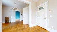 Located at 132 Franklin Street in downtown Rochester, NY, this one-bedroom, one-bathroom unit blends classic architectural character with functional living. Warm hardwood floors run throughout, complemented by tall white baseboards and period-appropriate details that speak to the building's historic roots. The entry greets you with a charming front door topped by a stained glass transom fanlight and an elegant chandelier overhead, setting a welcoming tone from the moment you arrive. The living room is bright and open, bathed in natural light from arched and double-hung windows, and features a cast-iron radiator that adds a touch of vintage charm. The bedroom, painted in a soft blue-gray hue, continues the hardwood flooring and is brightened by an arched window with serene treetop views. The compact kitchen offers warm oak cabinetry, a gas range, and ample counter and storage space, with a distinctive speckled floor. The bathroom features classic black-and-white checkered tile flooring, a pedestal sink, and a tub-shower combination, all accented by a window for natural ventilation. Throughout the space, the interplay of neutral tones, natural light, and timeless architectural details creates a cohesive and comfortable living environment.