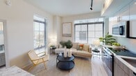 Located in the Capitol Hill neighborhood of Washington, DC, this modern single-floor residence at 1401 Pennsylvania Ave SE offers a thoughtfully designed layout with contemporary finishes throughout. Light hardwood flooring flows continuously through the open living, dining, and kitchen areas, creating a cohesive and airy feel.

The living room is bright and welcoming, featuring large windows with horizontal blinds that filter natural light and offer views of the surrounding neighborhood. Track lighting accents the space from above. The adjacent dining area accommodates a marble-top table with modern seating, complemented by clean white walls and recessed lighting. The kitchen is outfitted with stainless steel appliances, white upper cabinetry, wood-toned lower cabinets, and white quartz countertops with open shelving for added functionality.

The two bedrooms are generously proportioned, each with large windows that invite natural light and offer outdoor views. The primary bedroom features a sliding closet door and ample wall space, while both rooms maintain the home's neutral, calming aesthetic with light hardwood floors. The bathroom is finished with a floating wood-grain vanity, white quartz countertop, a large mirror, and clean tile flooring, reflecting a modern and polished sensibility throughout.