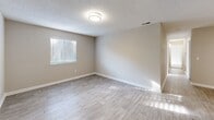 Located at 10920 Covington Bypass Rd in Covington, GA, this single-story, 3-bedroom, 2-bathroom home offers a well-organized layout designed for comfortable everyday living. The interior features a consistent neutral color palette with warm beige walls and crisp white trim throughout, creating a clean and cohesive aesthetic.

The kitchen is efficiently designed with white shaker-style cabinetry, marble-look countertops, and stainless steel appliances including a range, over-the-range microwave, and refrigerator. Light wood-look flooring ties the space together and extends into the main living areas.

The primary bedroom is generously proportioned, featuring plush carpet, a textured ceiling, and an en-suite bathroom. The en-suite includes a white vanity with marble-look countertop, a framed mirror, and a full soaking tub/shower combo. A dedicated walk-in closet with wire shelving provides ample storage.

The two additional bedrooms are carpeted and include built-in closets with bifold doors, offering practical storage for each room. The second full bathroom mirrors the same clean, updated finishes found throughout the home.

A connecting hallway links all rooms efficiently, and natural light filters into multiple rooms via window blinds. The textured ceilings and flush-mount lighting fixtures are consistent throughout, adding to the home's uniform and move-in-ready appeal.