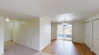 This single-floor residence offers a straightforward and functional layout designed for comfortable everyday living. The open living and dining area is finished with smooth hardwood-style flooring and is anchored by a decorative chandelier overhead. A sliding glass door floods the dining space with natural light and provides direct access to an outdoor area, creating a bright and welcoming atmosphere. The adjoining living room features neutral wall-to-wall carpeting and flows seamlessly into the rest of the home.

Multiple bedrooms are carpeted and bathed in natural light through standard windows that offer outdoor views of surrounding greenery. One bedroom includes a double-door closet, providing ample storage. The neutral, cream-toned walls throughout the home contribute to a clean and versatile aesthetic.

The kitchen is equipped with white cabinetry accented by wood-toned trim, dark speckled countertops, a stainless steel sink, a coil-top range, a dishwasher, and a refrigerator. Resilient tile-style flooring adds durability to this workspace. Two bathrooms serve the home, each featuring white square tile wainscoting, a vanity with a wood-framed medicine cabinet mirror, and clean, functional fixtures. The overall ambiance is bright, neutral, and move-in ready.