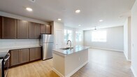This single-floor residence offers a thoughtfully designed open-concept layout that seamlessly connects the kitchen, dining, and living areas. The kitchen serves as the heart of the home, featuring a central island with a granite countertop and integrated sink, rich dark-toned cabinetry, a full suite of stainless steel appliances including a refrigerator, electric range, and over-the-range microwave, and a classic subway tile backsplash. Recessed lighting illuminates the space, complementing the warm, light-toned hardwood flooring that extends throughout the entire residence. The open living area is bathed in natural light from multiple windows and is equipped with a ceiling fan for added comfort. A clean, well-lit hallway connects the main living spaces to the private areas of the home. The bedrooms are generously sized, each featuring ceiling fans, neutral-toned walls, and large windows fitted with horizontal blinds that allow for adjustable natural light. The bathroom is neatly appointed with a granite-topped vanity, a soaking tub with a tiled surround, and direct access to a walk-in closet. The overall ambiance of the space is modern, clean, and move-in ready, with a neutral color palette that provides a versatile backdrop for any interior style.