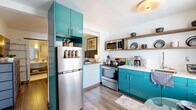 Located at 2735 N Monroe St in Tallahassee, FL, this thoughtfully designed one-bedroom, one-bathroom unit on the second floor makes excellent use of its compact footprint. The open layout connects the bedroom and kitchen through a distinctive pass-through window framed by a half-wall, creating a sense of connectivity while maintaining defined spaces.

The bedroom is the largest room in the unit, featuring dark hardwood-style flooring, a ceiling fan, and a wall-mounted mini-split HVAC system for efficient climate control. A rustic sliding barn door adds character and serves as a space-saving entryway feature. A bold vintage Casablanca movie poster anchors the room's retro aesthetic.

The kitchen is a standout, showcasing vibrant teal cabinetry paired with stainless steel appliances, including a full-size refrigerator, gas range, and microwave. Open wooden shelving provides additional storage and display space, while a window allows natural light to fill the area. A small dining space with a glass-top table completes the kitchen zone.

The bathroom features classic hex-tile flooring, a marble-look tiled tub and shower surround, and a clean white vanity with a modern countertop. The overall design balances retro charm with functional, modern finishes throughout.