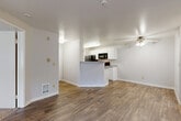 Located at 8710 Fifth Ave W in Everett, Washington, this single-floor, three-bedroom, two-bathroom home offers a practical and comfortable layout. The open-concept living and kitchen area serves as the heart of the home, featuring durable wood-style flooring throughout. The living room is highlighted by a classic white brick fireplace and a sliding glass door that opens to an outdoor patio, filling the space with natural light and views of the surrounding greenery. The kitchen is efficiently designed with white cabinetry, gray countertops, a peninsula with a built-in sink, and black appliances including a refrigerator, range, and microwave. A ceiling fan adds comfort to the combined living space. The three bedrooms offer a mix of flooring, with some featuring plush carpeting and others continuing the wood-style floors. The primary bedroom includes a walk-in closet with a double hanging rod. The two bathrooms are clean and functional, each equipped with a tub-shower combination. One bathroom features wood-style tile flooring and a vanity with white cabinetry and gray countertops. A hallway connects the bedrooms, and a dedicated closet provides additional storage throughout this well-organized home.