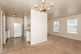 This single-floor residence in Columbus, Georgia offers a straightforward and functional layout across several well-defined rooms. The dining area makes a notable impression with its classic chandelier and clean white walls, creating a bright and inviting atmosphere. Soft, neutral-toned carpeting flows throughout the living and sleeping areas, lending a consistent and comfortable feel to the interior.

The kitchen is designed in a galley configuration, maximizing efficiency with white cabinetry lining both sides of the corridor. Warm wood-toned countertops provide ample workspace alongside a built-in sink, and the space is equipped with a full-size refrigerator. The tile flooring in the kitchen adds a practical, easy-to-maintain surface.

The bedrooms are generously proportioned, each featuring plush carpeting and neutral wall tones that create a calm, restful environment. Multiple windows fitted with horizontal blinds allow natural light to filter in, brightening each room throughout the day. The floor plan, as seen from above, reveals a compact yet well-organized arrangement with clear separation between the living, sleeping, and utility areas.

The bathroom includes a full tub and shower combination with tiled walls in a warm beige tone, complemented by tile flooring. Clean white fixtures complete the space with a timeless, functional aesthetic throughout this Columbus home.