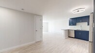 Located at 12155 W 58th Pl in Arvada, Colorado, this well-appointed 2-bedroom, 2-bathroom single-floor unit offers a thoughtfully designed open-concept layout with modern finishes throughout. Light-toned luxury vinyl plank flooring spans the living areas and bedrooms, creating a bright, cohesive aesthetic complemented by crisp white walls and clean baseboard trim.

The kitchen is the standout feature of the space, showcasing bold navy shaker-style cabinetry that extends to the ceiling for generous storage, paired with granite countertops and a white tile backsplash. A peninsula with a waterfall-edge granite counter adds seating and workspace, while stainless steel appliances — including a French door refrigerator, range, microwave, and dishwasher — complete the contemporary look.

The open living room benefits from recessed lighting and a large sliding glass door fitted with vertical blinds, inviting natural light and providing outdoor access. A baseboard heating unit ensures year-round comfort. Both bathrooms feature large-format white tile surrounds in the tub/shower combinations, navy vanities with white countertops, and tile flooring, echoing the kitchen's design palette. The primary bedroom offers a comfortable footprint with ample closet space. Three closets throughout the unit provide excellent storage capacity.