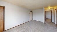 Located at 4979 S Washington Rd in Saginaw, Michigan, this 2-bedroom, 1-bathroom unit offers a practical and well-organized single-floor layout. The living room features plush carpeting, a textured ceiling, warm wood-paneled accents, and a large picture window that fills the space with natural light and outdoor views. The combined dining and kitchen area is fitted with white cabinetry, a marbled countertop with a built-in sink, wood-look vinyl flooring, and white appliances including a refrigerator and electric range. The primary bedroom is a comfortable, well-sized room with carpeted floors, a built-in louvered closet, and a sliding glass door that opens directly onto a private balcony overlooking the exterior. The second bedroom also features carpeting, a closet, and a window for natural light. The full bathroom includes a tub-shower combination, a vanity, and wood-look tile flooring with a small privacy window. A hallway connects the main living areas to the bedrooms and bathroom, and three closets throughout the unit provide ample storage. The textured ceilings and warm wood-toned door trim are consistent throughout, lending a cohesive and functional character to the space.