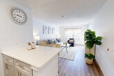 Located at Providence Village Drive in Sterling, Virginia, this single-floor, one-bedroom, one-bathroom residence offers a thoughtfully designed open-concept layout that maximizes its efficient footprint. Light-toned walls and wood-look flooring run throughout the main living areas, creating a bright and cohesive aesthetic.

The kitchen is well-equipped with gray shaker-style cabinetry, stainless steel appliances including a dishwasher, range, and microwave, complemented by a striking blue-and-white mosaic tile backsplash and white quartz countertops. A peninsula counter provides additional prep space and serves as a natural divider between the kitchen and living area.

The living room is open and inviting, bathed in natural light from a large window with a decorative valance. The entryway flows seamlessly into this space, highlighted by warm wood-look flooring and a textured accent wall.

The bedroom offers plush carpeting, a generously sized window with curtains, and two closets for ample storage. The bathroom features wood-look flooring, a white vanity with quartz countertop, a mirrored medicine cabinet, and clean, neutral finishes throughout. This residence combines practical functionality with a clean, modern aesthetic.