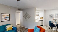 Located at 5215 West Peoria Avenue in Glendale, Arizona, this single-story 1-bedroom, 1-bathroom residence offers a thoughtfully designed layout across a compact yet functional floor plan. The living room serves as the heart of the home, featuring wood-look flooring, a textured ceiling, and a ceiling fan. A sliding glass door floods the space with natural light and provides direct access to an outdoor area, while a front entry door adds convenience. The living area flows seamlessly into a dedicated dining nook, which offers a cozy, defined space ideal for everyday meals. The galley-style kitchen is well-equipped with white shaker cabinetry, light quartz countertops, stainless steel appliances including a range, microwave, and dishwasher, plus a stainless steel sink with open shelving for additional storage. A hallway connects the main living areas to the private bedroom, which features plush carpeting, crown molding, a textured ceiling, and a window that brings in natural light. The full bathroom is finished in a clean, modern palette with white cabinetry, a quartz vanity, a large mirror, and a shower-tub combination. Wood-look tile flooring completes the bathroom's cohesive aesthetic.