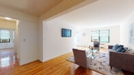 This single-floor residence at 100 Hoyt Street in Stamford, Connecticut, offers a thoughtfully arranged layout with consistent design details throughout. Warm-toned hardwood floors extend across the living areas and bedrooms, providing a cohesive aesthetic that ties the space together.

The living room is generously proportioned, featuring clean white walls, a wall-mounted television, and ample room for comfortable seating arrangements. It flows naturally into a dedicated dining area, which benefits from multiple windows overlooking greenery, filling the space with natural light and pleasant outdoor views.

The kitchen is functionally designed with oak cabinetry offering substantial storage, light-toned countertops, tile flooring, and essential appliances including a gas range, refrigerator, and dishwasher. A doorway from the kitchen provides convenient access to additional areas of the unit.

The space includes multiple bedrooms, each featuring hardwood floors, neutral walls, and windows that bring in natural light. Radiator heating units are present, along with window air conditioning units. The bathroom is finished with classic white tile on the walls and floor, a mirrored medicine cabinet, and a clean, straightforward layout.

Overall, the space presents a functional and well-lit environment with consistent finishes throughout.
