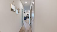 Located at 110 1 Mile Parkway in Nashville, TN, this 2-bedroom, 2-bathroom residence offers a thoughtfully designed single-floor layout that maximizes functionality and comfort. A clean, light-filled hallway with wood-look flooring and recessed lighting serves as the central corridor, connecting all areas of the home seamlessly.

The kitchen is a standout feature, showcasing a two-tone cabinet design with white upper cabinets and gray lower cabinets, dark granite countertops, a classic subway tile backsplash, stainless steel appliances, and a navy blue island — ideal for both cooking and casual dining. The adjacent living room is bright and inviting, benefiting from large windows with sheer curtains that allow generous natural light, complemented by wood-look flooring and an open, airy atmosphere.

The primary bedroom offers a comfortable, carpeted retreat with ample space, a closet, and access to one of the two full bathrooms. The second bedroom also features carpet, natural light from windows, and its own closet. Both bathrooms are finished consistently with wood-look tile flooring, white rectangular tile tub surrounds, and dark granite vanity tops, delivering a clean and modern aesthetic throughout. The layout also includes a dedicated hallway and two closets for added storage convenience.