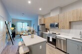 Located at 2119 Post Rd in Warwick, Rhode Island, this thoughtfully designed one-bedroom, one-bathroom unit offers a modern and efficient single-floor layout. The open-concept living area seamlessly connects the kitchen, dining, and living spaces, creating a bright and cohesive environment filled with natural light from large windows dressed with sheer curtains.

The kitchen is a standout feature, showcasing two-toned cabinetry with warm wood upper cabinets and sage-gray lower cabinets, crisp white quartz countertops, a subway tile backsplash, and a full suite of stainless steel appliances including a gas range, microwave, refrigerator, and dishwasher. A peninsula with bar seating adds both function and style, flowing naturally into the dining and living area.

The living room is comfortably scaled with light-toned hardwood-style flooring that runs throughout the unit, neutral gray walls, and ample room for relaxing or entertaining. The bedroom is a quiet retreat with natural light, a window with sheer treatments, and space for a full furniture arrangement. Two closets provide generous storage throughout the unit. The bathroom features a clean, modern design with a tub-shower combo, white tile surround, and a vanity with gray cabinetry. An in-unit laundry area and utility room add everyday convenience.