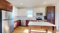 Located at 201 Eldorado Dr in Jordan, MN, this 2-bedroom, 1-bathroom unit offers a well-designed, single-floor layout with a clean, modern aesthetic throughout. The open-concept kitchen and living area serves as the heart of the home, featuring rich walnut-toned lower cabinetry paired with crisp white upper cabinets and a geometric tile backsplash. A full suite of stainless steel appliances — including a refrigerator, electric range, microwave, and dishwasher — complement the white quartz countertops. A freestanding kitchen island provides additional prep and storage space. Light wood-look flooring runs consistently throughout the unit, creating a warm, cohesive feel. The spacious primary bedroom benefits from a wall of windows that invite generous natural light and outdoor views, while the second bedroom is bright and well-proportioned. The bathroom is outfitted with a tub-shower combo and wood-look flooring. A separate walk-in shower with built-in shelving is also present. Additional spaces include multiple closets for ample storage, a dedicated laundry area, and a utility room, rounding out the practical and functional layout of this well-appointed unit.